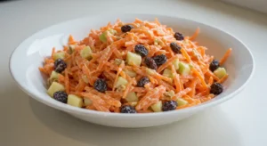 Homemade carrot raisin salad in a large white dish on a kitchen counter