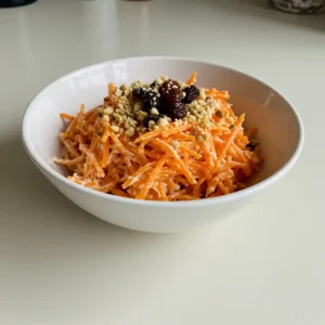 Carrot raisin salad served with chopped nuts on a white bowl