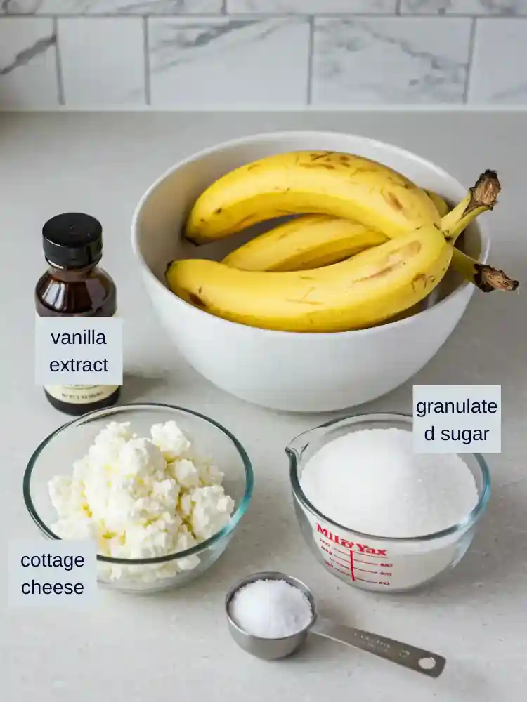 A collection of key ingredients for making cottage cheese banana bread, including ripe bananas, cottage cheese, sugar, and vanilla extract, neatly arranged on a clean kitchen countertop.
