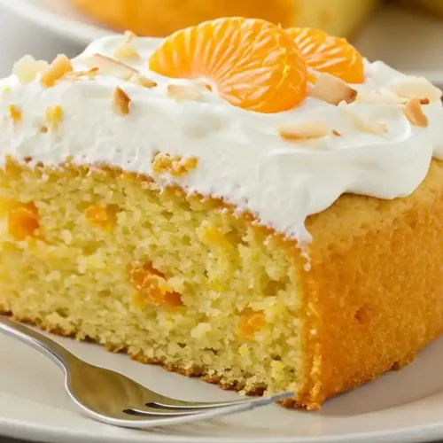 Mandarin Orange Cake: Easy & Moist 4 Close-up of a moist mandarin orange cake slice with creamy frosting and orange pieces.