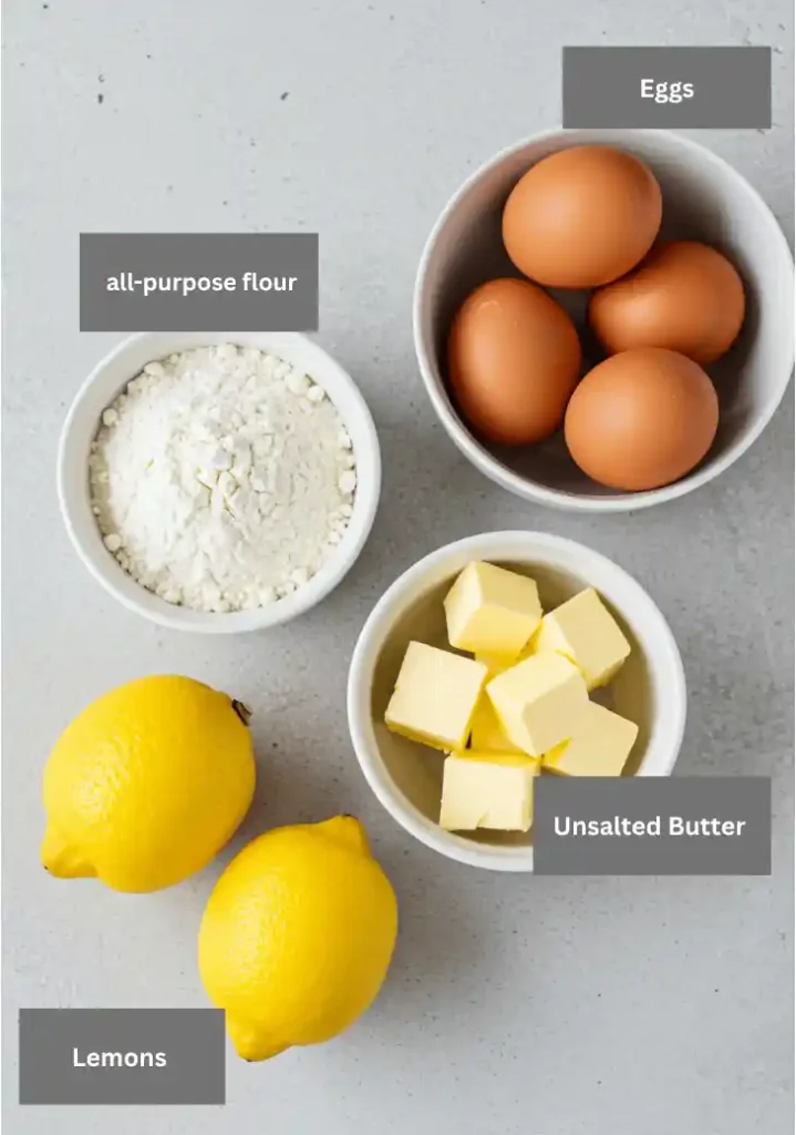 My Best Lemon Tart Recipe 2 Ingredients for a lemon tart, including flour, cold butter, eggs, and fresh whole lemons, arranged on a countertop.